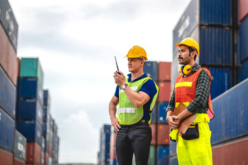 Wall Mural - Professional of two engineer container cargo foreman in helmets working standing and using walkie talkie checking stock into container for loading.logistic and business export