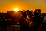 Fototapeta Londyn - A couple is watching the sunset over the city from the observation deck in Warsaw, Poland (Lens Flair)