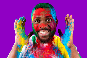 Afro american man celebrate holi festival in violet studio background