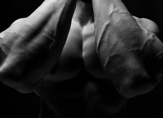 Closeup image of strong tight bodybuilder arms hands chest after fitness working out training. Black and white composition