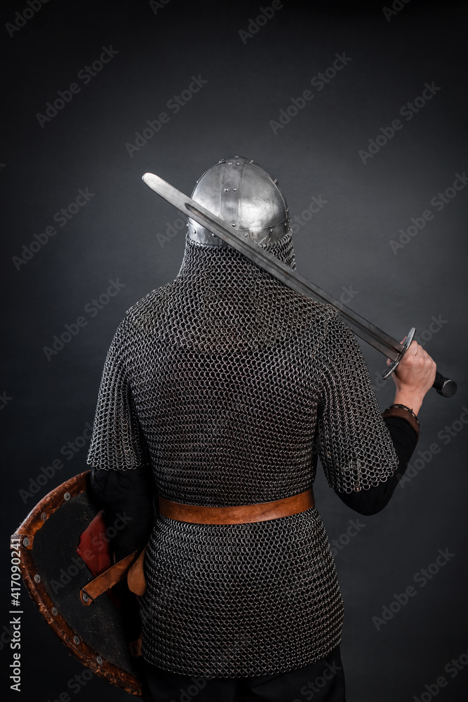 Back view of a knight in chain mail and a helmet with a sword on his ...