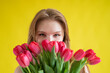 © Михаил Решетников - Woman with a bouquet of red tulips on a yellow background. Happy girl in a black dress holds an armful of flowers . Gift for Valentine's Day. The most romantic day of the year.