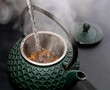 eau chaude versée dans une théière type asiatique sur une table noire