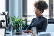 © nenetus - Beautiful young afro business woman working while making video call with computer sitting in the office.