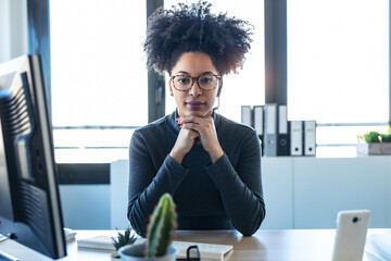 Wall Mural - Beautiful afro business woman relaxing while looking at camera in the office.