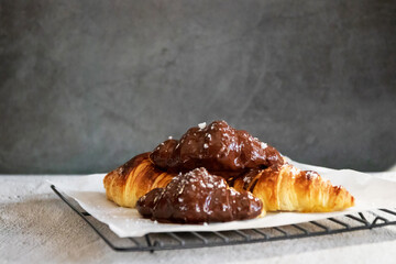 Wall Mural - Dark chocolate croissants with nut and flower of salt on top in vintage dark stone background. Tasty and freshly croissants. 