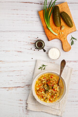 Wall Mural - Thick hearty Pickle soup with vegetables (pickles, cucumbers, carrots, onions, potatoes, tomatoes) and pearl barley in a white plate on a wooden table. Rassolnik. Russian cuisine.  Copy space