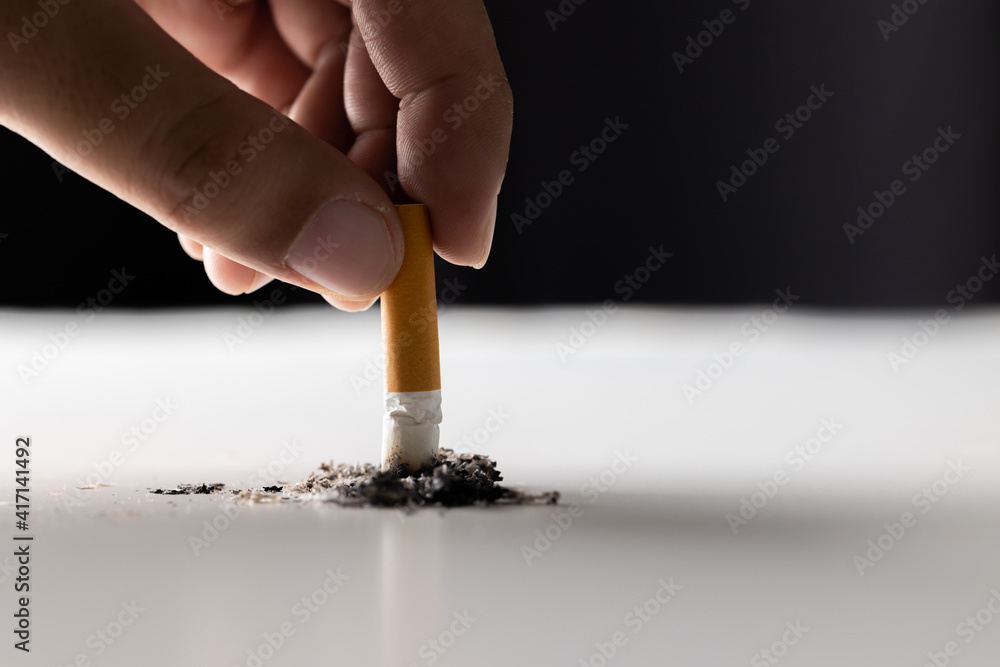 put out a cigarette Close up hand putting out a cigarette. man extinguished his cigarette by  crushing the floor. He smoked a lot of cigarettes Stock Photo