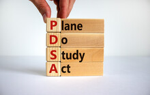 PDSA, Plan Do Study Act Symbol. Businessman Hand. Wooden Cubes And Blocks With Words 'PDSA, Plan Do Study Act'. Beautiful White Background, Copy Space. Business And PDSA, Plan Do Study Act Concept.