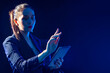 © Grispb - Businesswoman with a tablet in hands. Woman with a tablet stretches hand forward. Businesswoman on a dark background. Woman in a business jacket. Young woman look into tablet. Place for inscription.