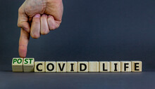 Symbol for a post-covid life. Businessman turns cubes and changes words 'covid life' to 'post-covid life'. Beautiful grey background. Medical, business and covid-19 pandemic concept, copy space.