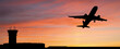 Silhouette of a plane landing at the airport against the background of sunset
