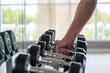 © Sathaporn - Close up man hand picking or choosing dumbbell from dumbbell racks at the gym.