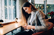 © GalakticDreamer - Focused woman browsing mobile phone in light cafe