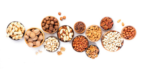 Wall Mural - Assortment of nuts in bowls. Cashews, hazelnuts, walnuts, pistachios, pecans, pine nuts, peanuts, macadamia, almonds, brazil nuts. Food mix on white background, top view, copy space