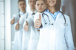 © Iryna - Group of modern doctors standing as a team with thumbs up in hospital office. Medical help, insurance in health care, best desease treatment and medicine concept