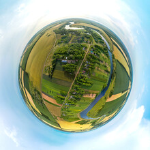 Little Planet 360-pano - Summer Landscape Of A Street In The Village Of Sredny Near A Deep River Surrounded By Green And Yellow Fields Of A Blue Lake Under The Sky With Clouds Among Green Fields On A 