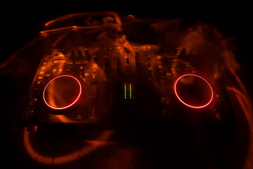 Wall Mural - DJ console deejay-mixing desk in dark with colorful light. Mixer equipment entertainment DJ station.