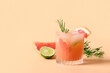canvas print picture - Grapefruit soda with lime garnish rosemary sprig on color beige background. Mocktail Paloma. Close up.