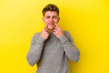 Young caucasian man isolated on yellow background doubting between two options.