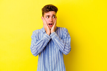 Wall Mural - Young caucasian man isolated on yellow background scared and afraid.