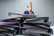raised hands of a person who sinks behind stacks of ring binders on an office desk. concept of excessive demands and increasing work in business. selected focus.