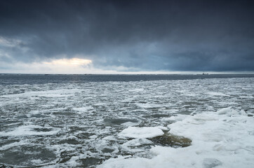 Wall Mural - Frozen Baltic sea shore, ice fragments close-up. Dramatic sky, dark clouds. Winter landscape. Concept image. Seasons, nature, ecology, environment, climate change, global warming