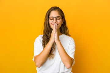 young caucasian woman holding hands in pray near mouth, feels confident.