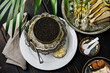 © The Picture Pantry - Black caviar in can on ice in silver bowl and Champagne on black wooden background close-up