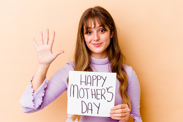 Wall Mural - Young caucasian woman holding a Happy mothers day placard isolated smiling cheerful showing number five with fingers.
