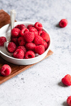 Fresh Raspberries In A Shallow Dish With A Spoon Sitting On A Cutting Board.