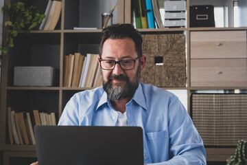 Wall Mural - one young man working at home in the office with laptop and notebook talking in a video conference. One businessman calling communicating