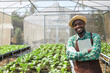 A black man holding a tablet on a vegetable farm.
