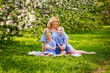 © Elena  - Happy chubby mom and two kids boy and girl in a blooming spring apple orchard on a spring picnic.
