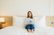 © siraphol - Portrait beautiful young asian woman use computer laptop on bed