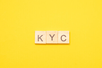 Word KYC made from wooden letters on yellow background. Acronym Know Your Customer