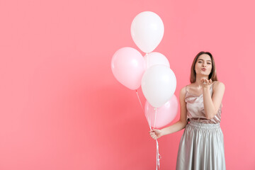 Poster - Beautiful young woman with balloons blowing kiss on color background