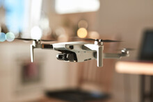 Testing New Drone Indoors With Apartment Interior Blurred In The Background. Close-up Shot Of A Drone. Sun Shining From The Window