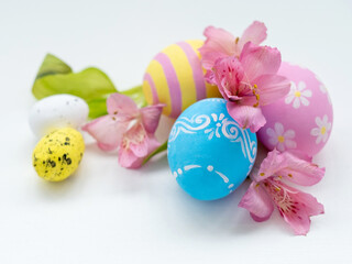 Spring composition. Easter decoration. Holiday ornament. Colorful blue pink yellow painted eggs with traditional and modern design flowers isolated on white background.