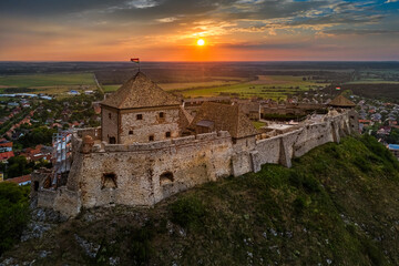 Wall Mural - Sumeg, Hungary - Aerial panoramic view of the famous High Castle of Sumeg (Sumegi var) in Veszprem county with beautiful dramatic clouds and colorful sunset at background on a warm summer afternoon