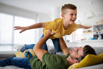 Cheerful young boy having fun with father together at home