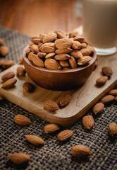 Wall Mural - Almond milk in the glass with almond in the wooden bowl on the wooden table.