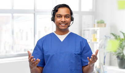 Wall Mural - medicine, profession and healthcare concept - happy smiling indian doctor or male nurse with headset over medical office at hospital background