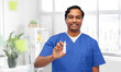 © Syda Productions - medicine, profession and healthcare concept - happy smiling indian doctor or male nurse in blue uniform with nasal spray over medical office at hospital background