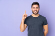 © luismolinero - Caucasian handsome man pointing up a great idea over isolated purple background