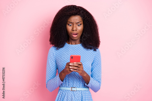 Photo of mad lady hold telephone look screen open mouth wear blue dotted dress isolated pink color background