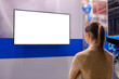 © zyabich - Woman looking at blank digital interactive white display wall at exhibition or museum with futuristic scifi interior. White screen, mock up, future, copyspace, template, technology concept