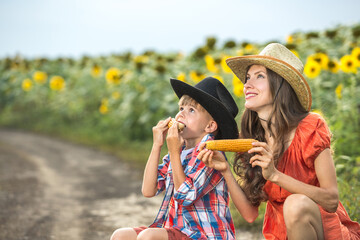 Beautiful mother and son eating corn outdoors