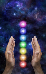 Wall Mural - Sending Distant Healing to the Seven Chakras - male parallel hands with a neat stack of seven rainbow coloured chakra vortexes between against a dark deep space background with copy space
