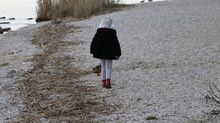 Baby Walking On The Rocky Shore By The Sea During The Daytime